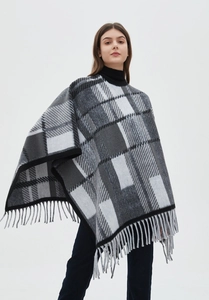 Detail of classic black and white plaid poncho with soft fringe hem and knit texture