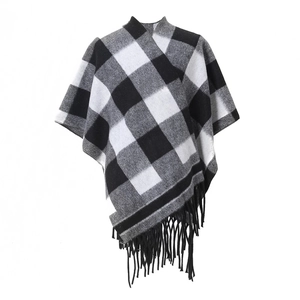 Close-up of black and white buffalo check knit poncho with long decorative fringe tassels