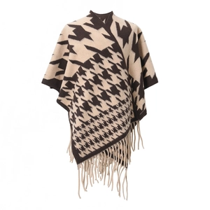 Detail of knit houndstooth poncho showing beige and coffee patterns with long fringe