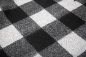 Close-up of thick black and white plaid wool blend fabric showing soft fibrous texture
