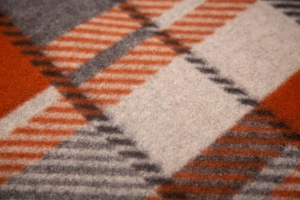 Macro shot of plaid woven fabric in orange and grey showing soft wool texture