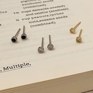 Close-up of three pairs of vintage zircon stud earrings placed on an open book page