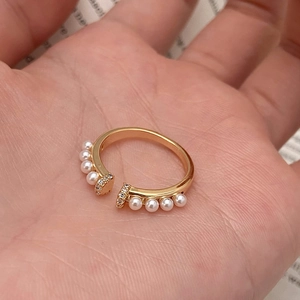 Bague ouverte vintage dorée avec perles et cristaux de zircon présentée sur une main
