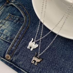 Dettaglio di pendenti a gatto minimalisti con madreperla bianca e catene in argento