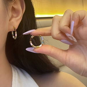 Detail view of colorful enamel segment hoop earrings with gold-plated metal finish
