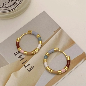 Macro detail of multi-color enamel bamboo hoop earrings with gold plated finish