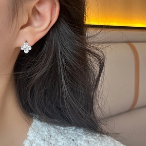 Gros plan d'une boucle d'oreille trèfle à quatre feuilles en zircon sur un mannequin