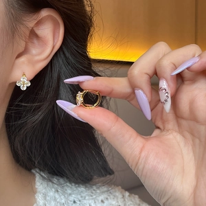 Détail macro de boucles d'oreilles trèfle dorées avec des zircons étincelants