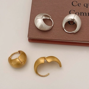 Macro detail of brushed matte gold and silver teardrop earrings with hinge mechanism