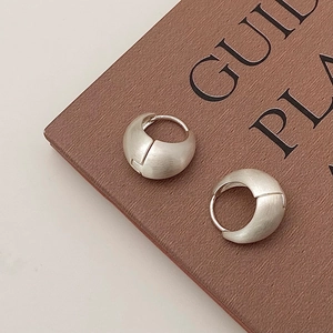 Macro detail of silver-finish matte brushed metal earrings on a vintage book