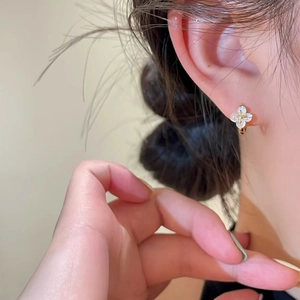 Boucles d'oreilles créoles trèfle dorées avec zircone cubique sur un mannequin