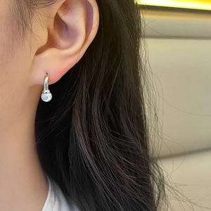 Gros plan d'élégantes boucles d'oreilles en perles blanches portées par un mannequin