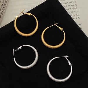 Chic gold and silver frosted hoop earrings with glitter texture on black velvet background
