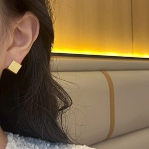 Minimalist square geometric earrings in matte gold finish shown on a female model