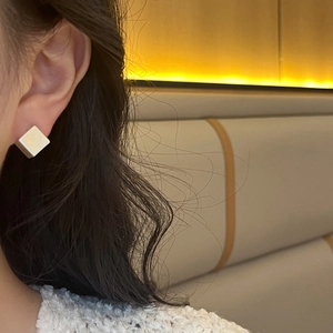 Minimalist geometric cube stud earrings with matte silver finish on female model