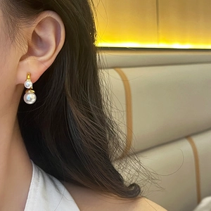 Élégantes boucles d'oreilles double perle dorées portées par un mannequin chic
