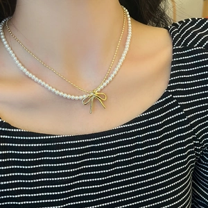 Detail einer doppelreihigen Schleifenkette mit Goldperlen und weißen Perlen am Hals