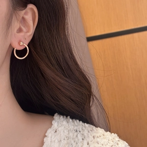 Close-up of rose gold horseshoe nail earring worn by a model in soft lighting