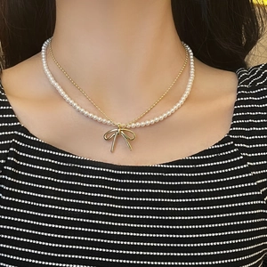 Zweilagige goldene Perlenkette mit weißen Perlen und einem polierten Schleifenanhänger