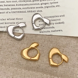 Set aus goldenen und silbernen herzförmigen Ohrringen auf Leinen und Vintage-Papier