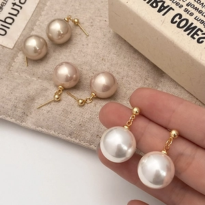 Close-up of three pairs of large champagne and white pearl earrings with gold studs
