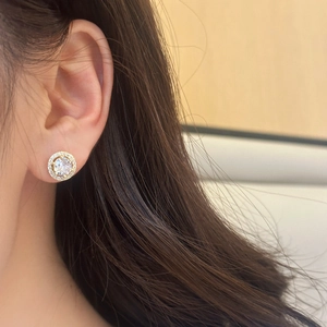 Elegant gold round stud earrings with halo-set cubic zirconia shown on model's ear