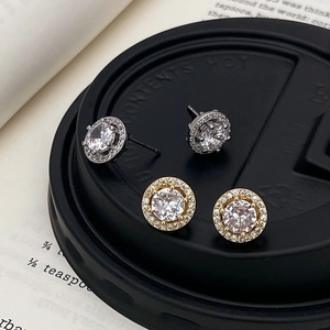Elegant gold and silver halo stud earrings with round cubic zirconia on a black surface