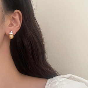 Detailed view of 10mm golden pearl earring with crown zircon accents on model ear