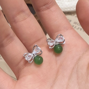 Boucles d'oreilles nœud en calcédoine verte et zircon présentées sur la main