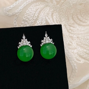 Detailed macro view of green chalcedony crown earrings with white zircon on a black stand