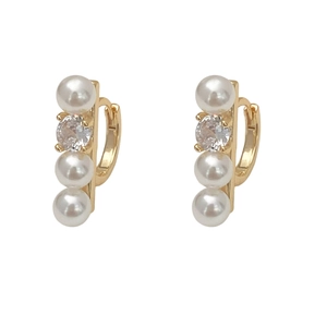 Detailed view of gold hoop earrings with three vertical pearls and a sparkling zircon stone