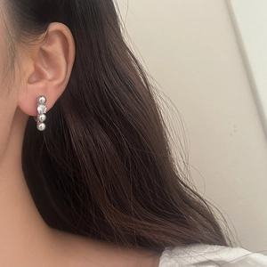 Elegant linear earrings with four grey pearls and a zircon stone shown on ear