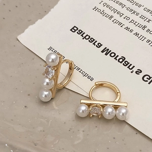 Detailed shot of French style gold hoop earrings with pearls and zircon crystals