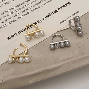 Elegant pearl and zircon earrings in gold and silver finish on a ceramic tray