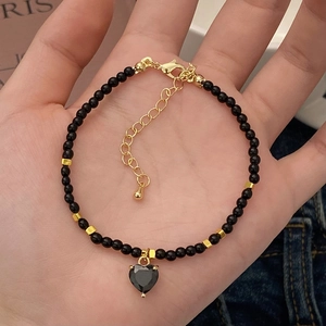 Ensemble collier et bracelet en perles noires avec pendentif coeur en main