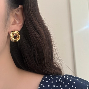 Close-up of triple-layered golden loop earrings on model with vintage aesthetic style