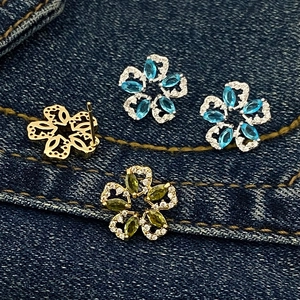 Olive green flower petal stud earrings with zircon inlay on blue denim background