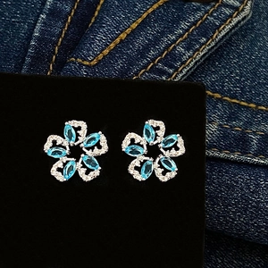 Macro view of flower-shaped blue zircon earrings with sparkling white stone petals