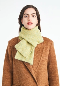 Detailed ribbed texture of soft wool knit scarf in pale green on a brown wool coat