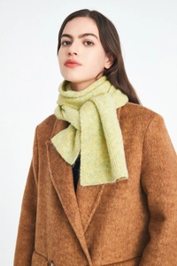 Close-up of light green knitted wool scarf with soft texture on dark brown winter coat