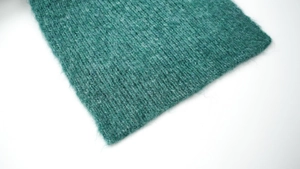 Macro detail of soft turquoise wool knit fabric showing premium ribbed texture