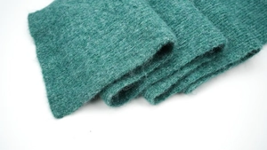 Detailed macro view of teal ribbed knit wool scarf showing soft texture and premium fibers