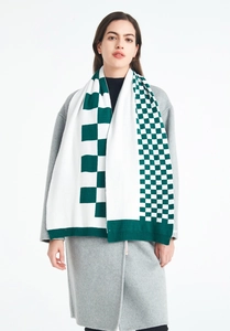 Detail of green and white checkerboard knit scarf texture with ribbed edge finish