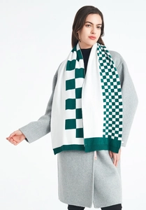 Detailed view of white and green checkered knit scarf with ribbed edges and soft texture