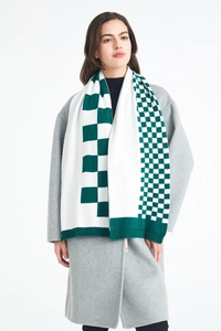 Detail of green and white asymmetrical checkerboard knit scarf with ribbed hem finish