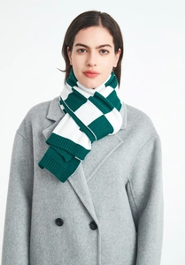 Detailed view of green and white checkered knit scarf with ribbed edges on a gray wool coat