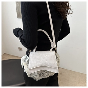 Detailed view of white crocodile pattern crossbody bag with knotted handles and gold buckle
