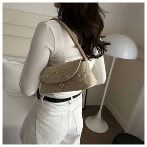 Detail of woven straw shoulder bag with purple floral embroidery and golden bow buckle