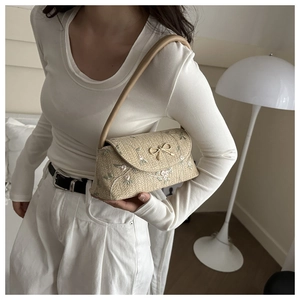 Détails de broderie florale et boucle dorée sur le sac baguette tissé beige