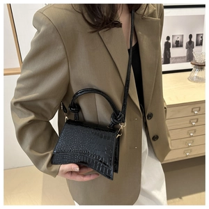 Detail of black crocodile texture mini bag with curved base and elegant knot handle
